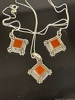 Pendant and earrings laid out showing design and chain