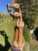 Full view of tall carved wood sculpture held outdoors