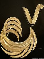 Front view of both Trifari gold-tone brooch pins showing designs