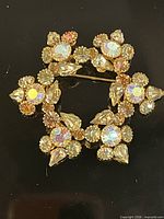 Front view of gold-tone brooch showing starburst arrangement of aurora borealis rhinestones