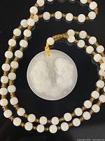 Full view of necklace showing white beads, amber beads and carved white pendant