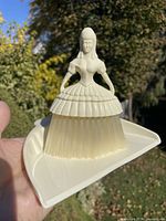 Full view of lady-shaped crumb brush seated on matching tray