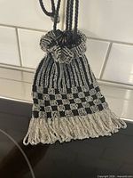 Full view of beaded evening bag hanging, showing checkerboard pattern and fringe