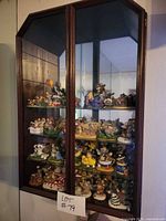 Tall wooden glass-front cabinet filled with numerous small mouse figurines