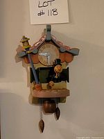 Front view of Disney Pinocchio drunk man cuckoo wall clock with pendulum and two pinecone weights visible