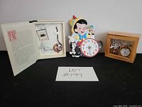 Group shot showing ceramic clock, open book-style display with pocket watch and separate boxed pocket watch