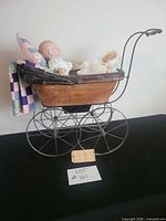 Full view of carriage with two dolls and textiles inside