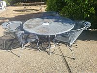 Full view of round metal mesh table and three chairs outdoors