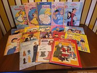 All 18 paper doll books laid out on table