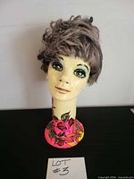 Front view of painted papier-mâché mannequin head with wig and floral base