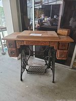 Full view of oak cabinet on cast iron base with treadle pedal, top closed