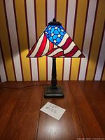 Full view of lamp on table, stained glass shade lit