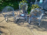 Full view of three wrought iron rocking chairs outdoors