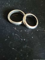 Two hematite rings lying flat on black surface