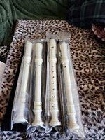 Four sealed cream plastic recorders side by side