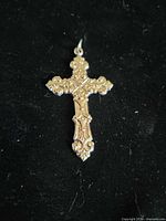 Front view of ornate chrome cross pendant