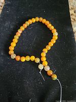 Strand of orange fire agate beads on black fabric