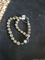 Strand of round flat jet beads coiled on black cloth