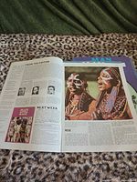 Open magazine pages featuring Masai article, background shows additional magazines stacked