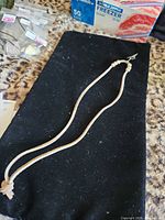 Full view of necklace laid flat showing overall length and cord material