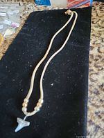 Full view of shark tooth leather necklace laid flat