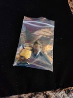 Six Tiger's Eye stones inside plastic bag on black background