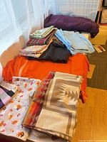 Overall lot showing stacked fabrics, throws and scarf