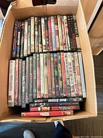 Box filled with DVDs spine-up showing assorted titles