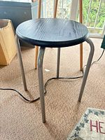 Black 3-leg metal stool with wood seat