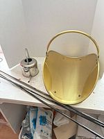 Brass scuttle, stainless watering can, three metal rods visible