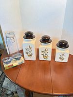 Full lot view: three ceramic canisters, clear clamp jar, blue bowls in box