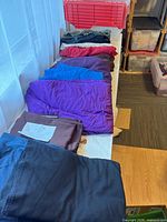 Stack of folded knit jersey fabrics showing black, brown, purple, blue, red pieces