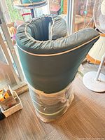 Rolled green sofa with cream trim wrapped in plastic, viewed from side