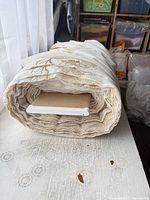 End view of rolled ivory sheer fabric showing layered yards and cardboard core
