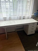 Full view of long white desk in front of window