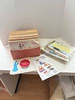 Overview showing red gingham box filled with pattern envelopes, loose Creative Patterns and Kwik Sew envelopes, plus plastic-bagged bundle