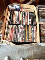 Cardboard box of assorted DVDs, spines visible