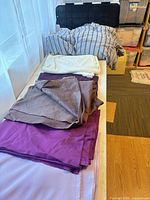 Stack of multiple fabric cuts in purple, glitter gray, bright purple, pink on bench