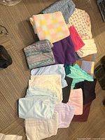 Group shot of folded fabrics and linens showing variety of colours, patterns and textures