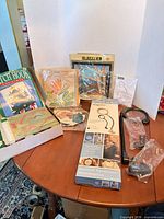 Full lot overview showing magnifier box, latch hook kit box, needlepoint kits and embroidery supplies