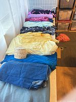 Stacked fabric pieces in various colours with spool of pearl trim visible