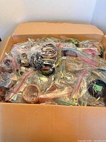 Open cardboard box filled with individually bagged bangles and bracelets