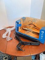 Mixed wooden, clear plastic and black plastic hangers on table, partial box shown