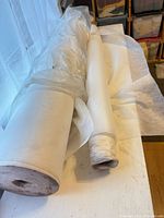 Two large rolls of white non-woven interfacing on table