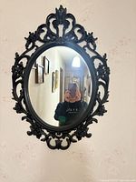 Full view of ornate oval black wall mirror