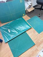 Four green cutting mats in assorted sizes displayed on floor, showing overall lot contents