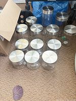 Group of clear glass jars with brushed stainless lids on floor