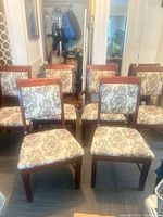Front view of six dining chairs showing upholstery and wood finish