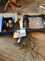 Handheld massager, Relaxus cushion, box with heads, manual visible on carpet