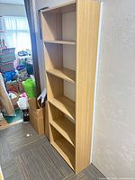Front angled view of tall narrow laminate bookcase with five shelves